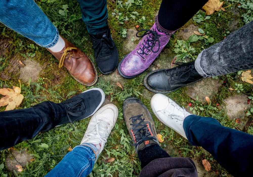 Draufsicht auf die bunten Schuhe der arbeitenden Menschen im Team ambulante Hilfen zur Erziehung, die in einem Kreis zusammen stehen