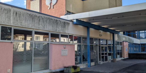 Blick auf den Eingang eines einstöckigen Schulgebäudes mit vielen Fenstern