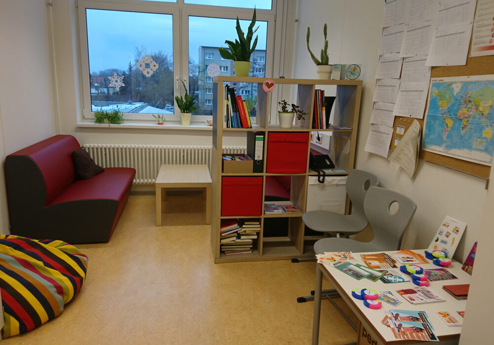 eine gemütliche Beratungsecke mit roter Couch und einem Regal im Raum mit Büchern und Broschüren