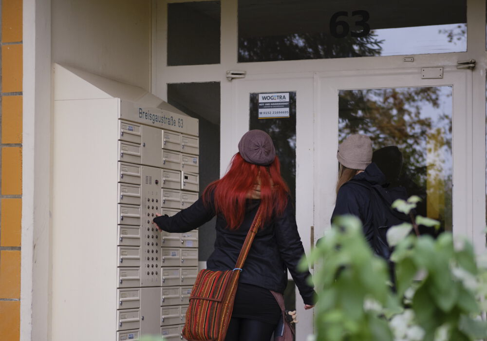 zwei Personen vor dem Eingang eines Hauses klingeln an der Tür