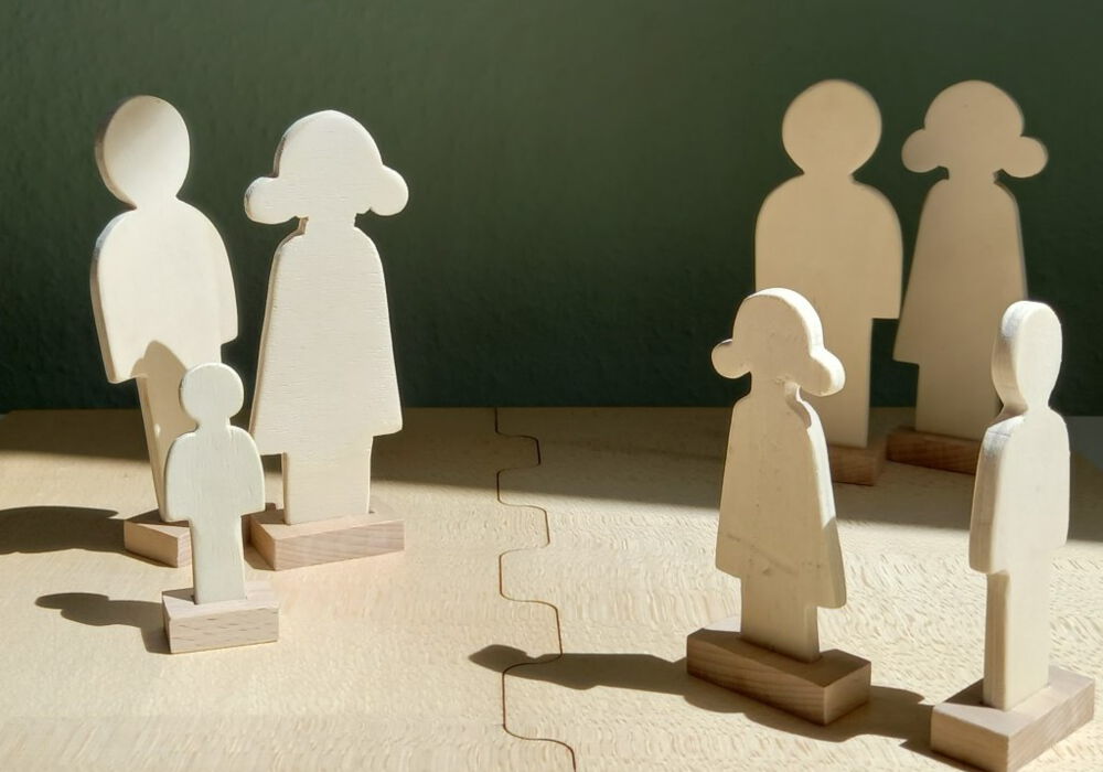 eine Familie aus kleinen Holzfiguren steht auf einem Holzspielbrett