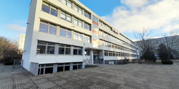 ein vierstöckiges Schulgebäude mit einem weitläufigen Schulhof