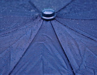 Nahaufnahme einer Regenschirmoberfläche mit Wassertropfen